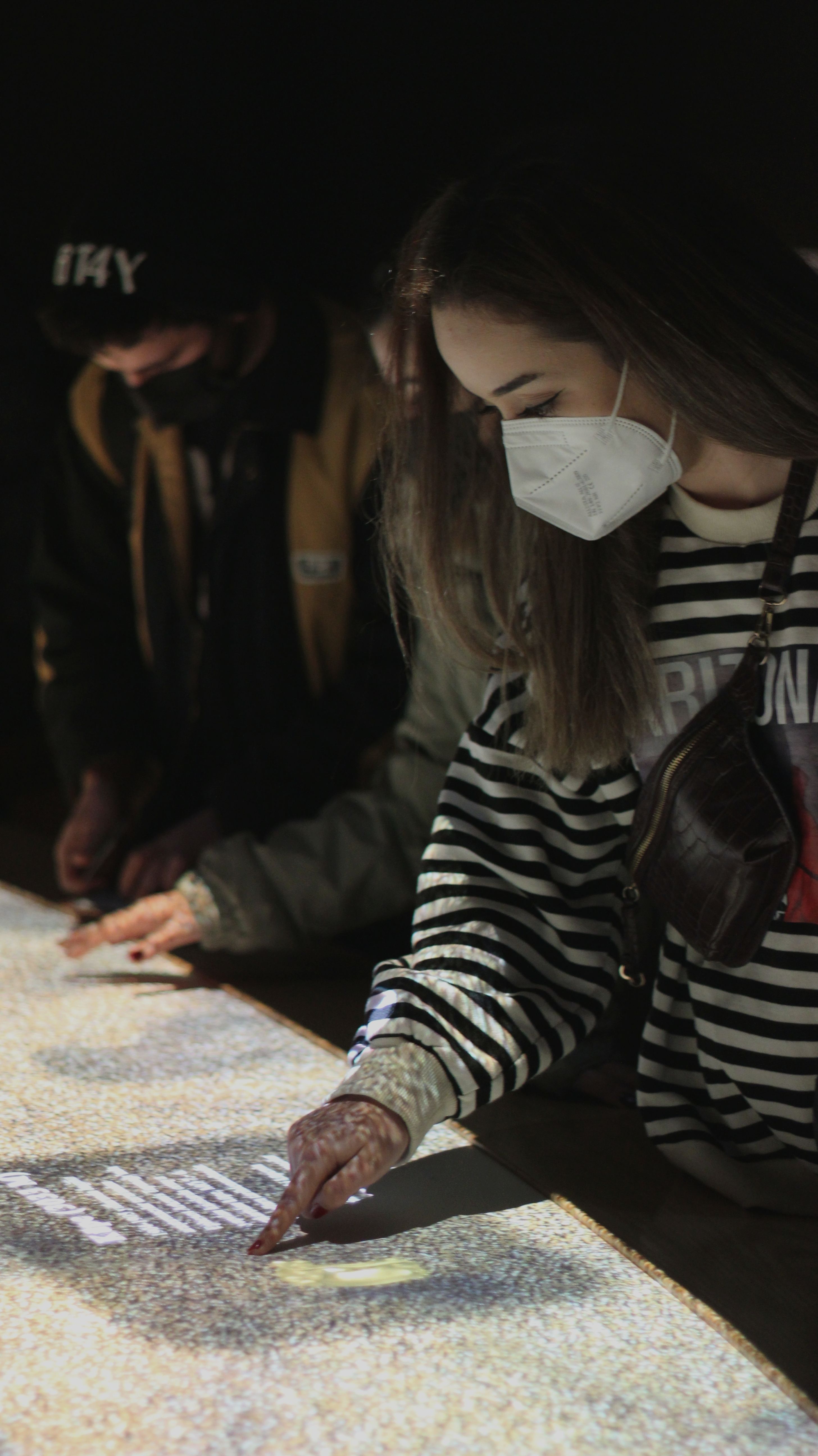 A woman wearing a face mask interacts with a digital display in Istanbul, Turkey, highlighting COVID-19 safety.