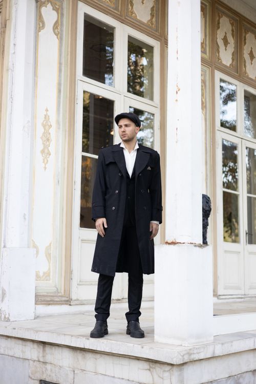 Free A caucasian man stands outdoors in a black trench coat in front of an ornate building in Turkey. Stock Photo