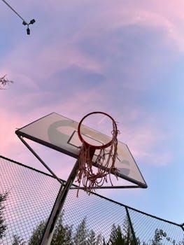 Low-angle shot of a damaged basketball hoop set against the twilight sky in Turkey.
