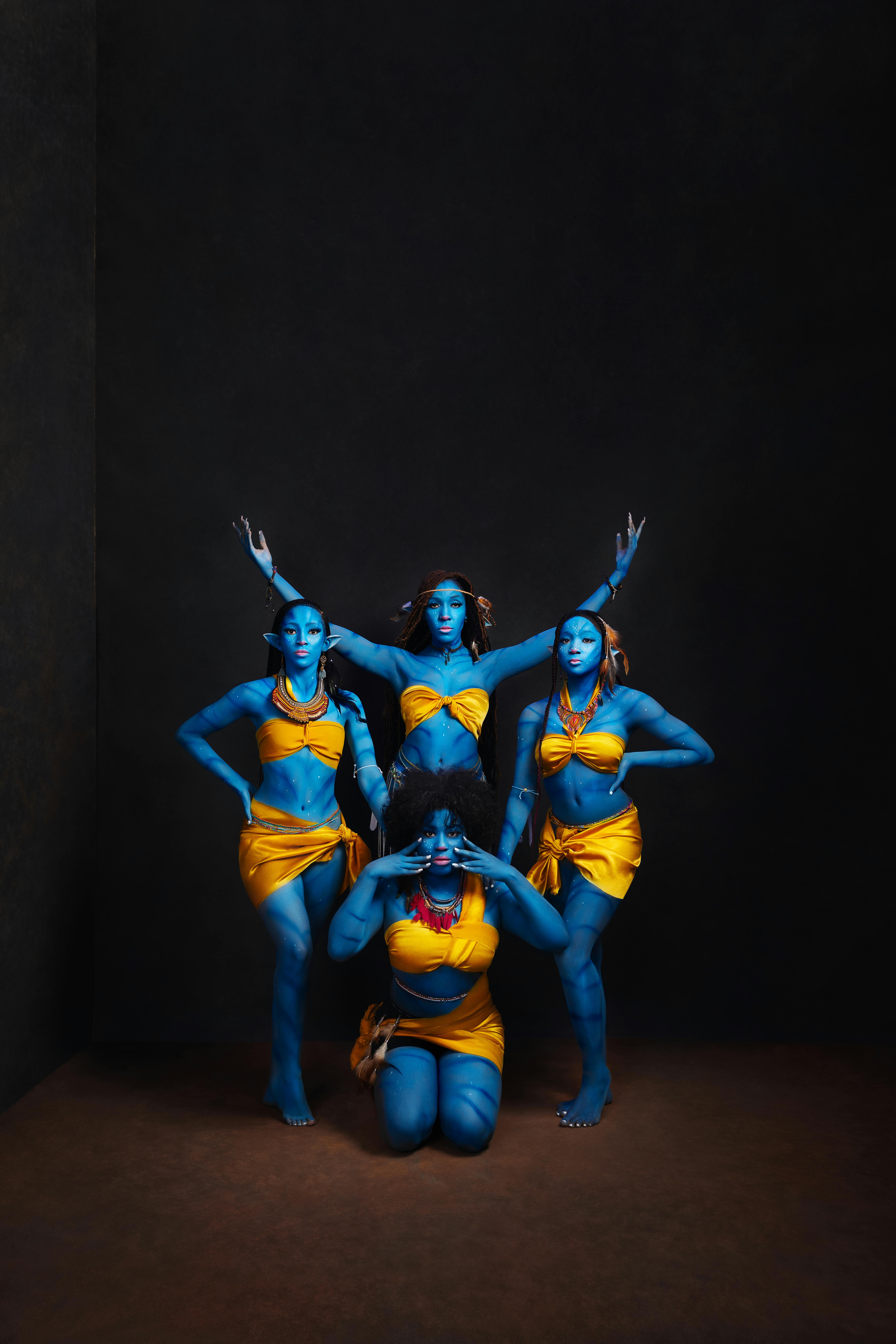 Free Four dancers in vivid blue body paint perform a synchronized pose in a studio, highlighting artistry and movement. Stock Photo