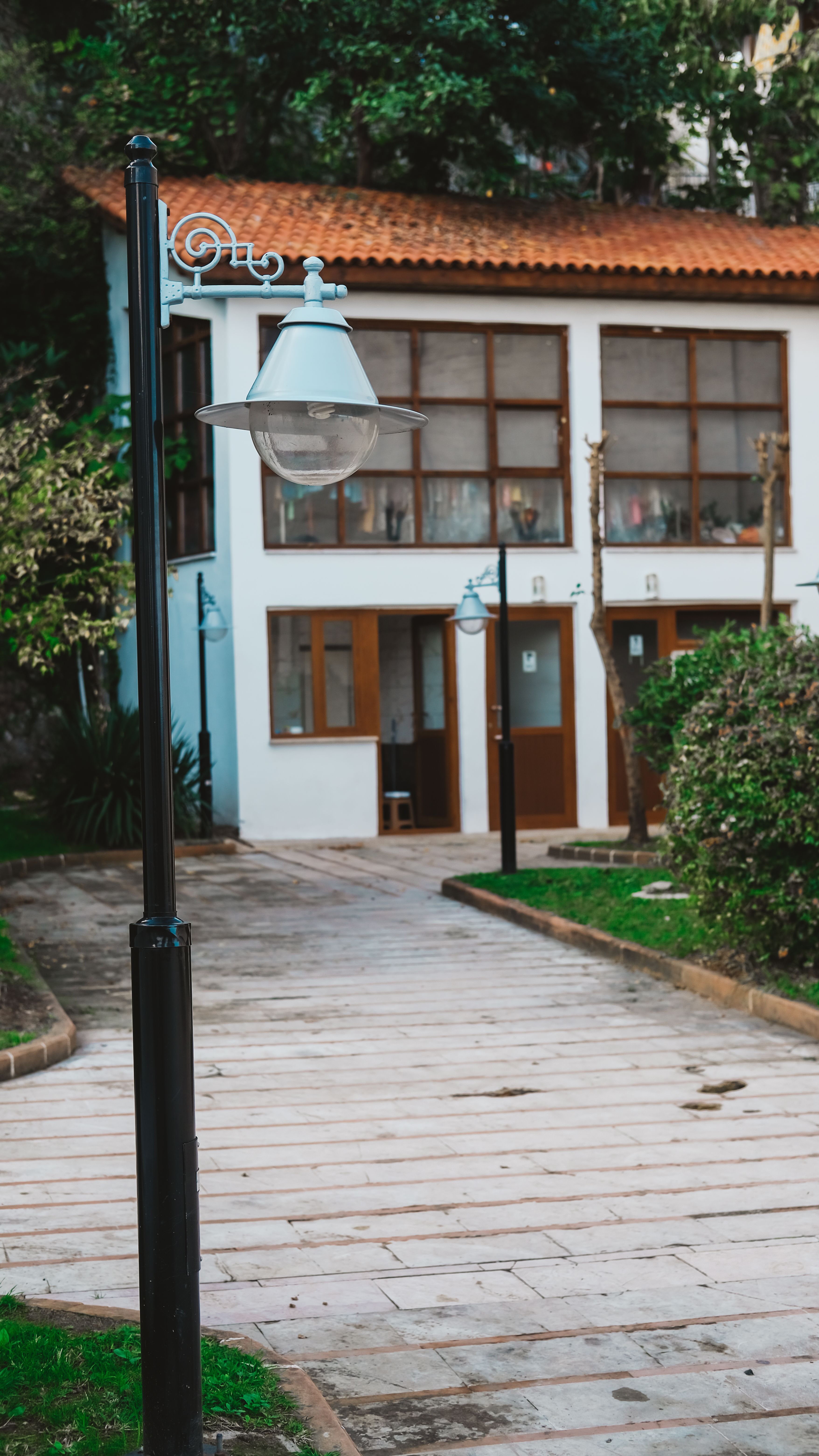 Charming walkway beside vintage street lamps leading to a quaint house with glass windows.