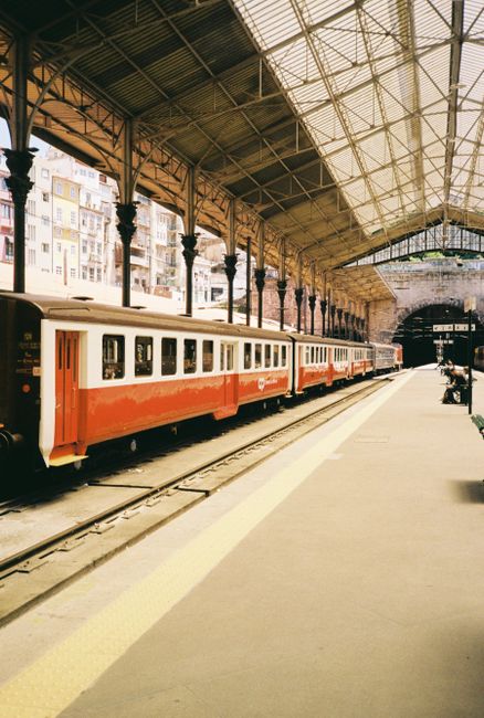 Vintage red train at a historic station with arched ceiling and platform.
