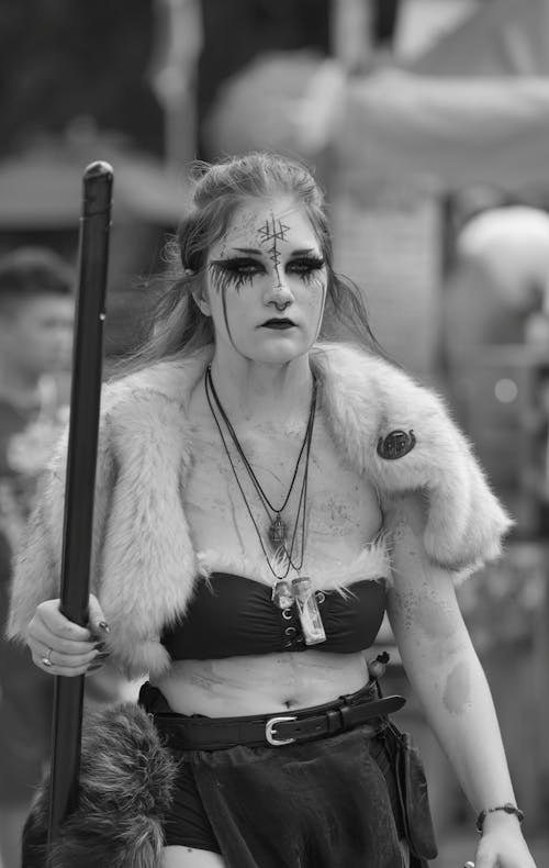 Grayscale Photo of a Woman in Fur Coat Holding a Wood
