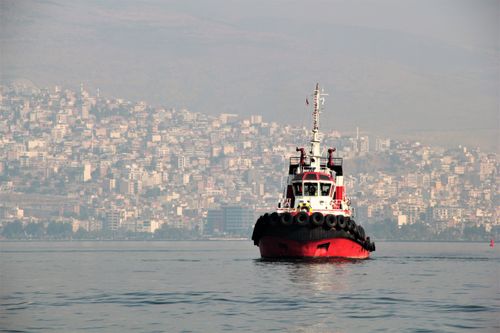 Free A solitary tugboat on the calm sea with Izmir cityscape in the background. Stock Photo