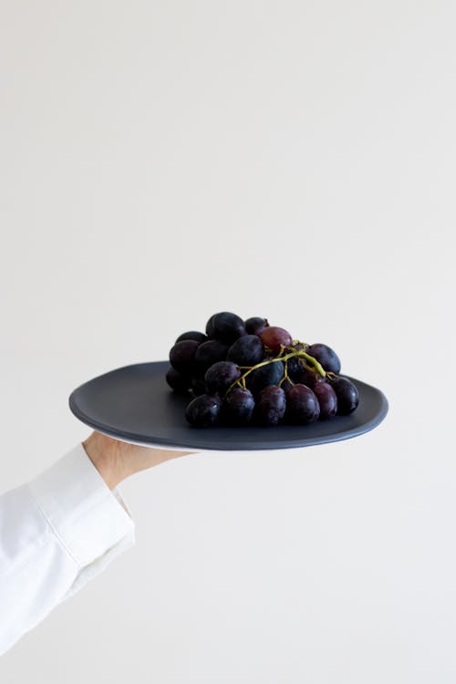 Hand Holding a Plate with Grapes