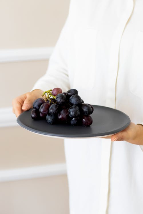 Person Carrying a Plate with Grapes