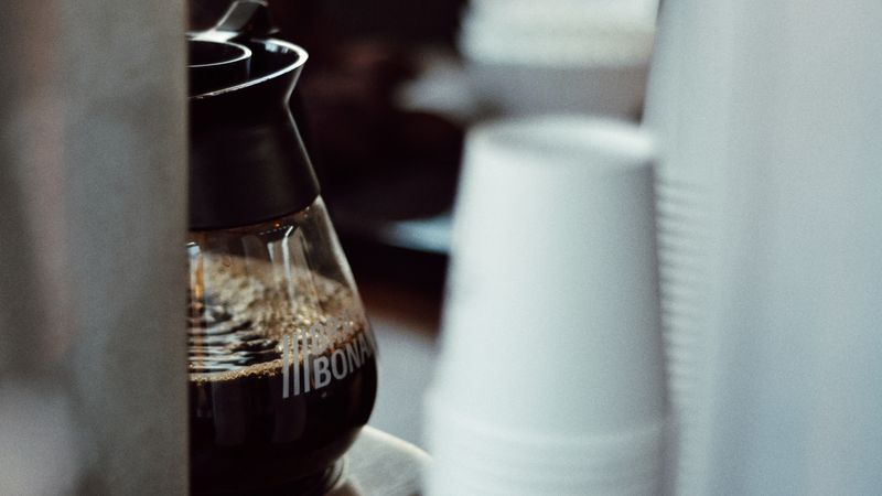 automatic drip coffee maker filling a glass carafe on a morning kitchen counter