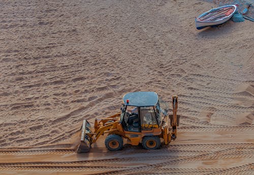 Aerial View of a Backhoe Loader Driving on a Beach 