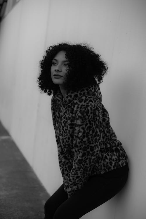 Woman in Leopard Print Coat Standing Beside White Wall