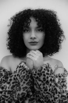 Elegant black and white portrait of a woman with curly hair and leopard print coat.