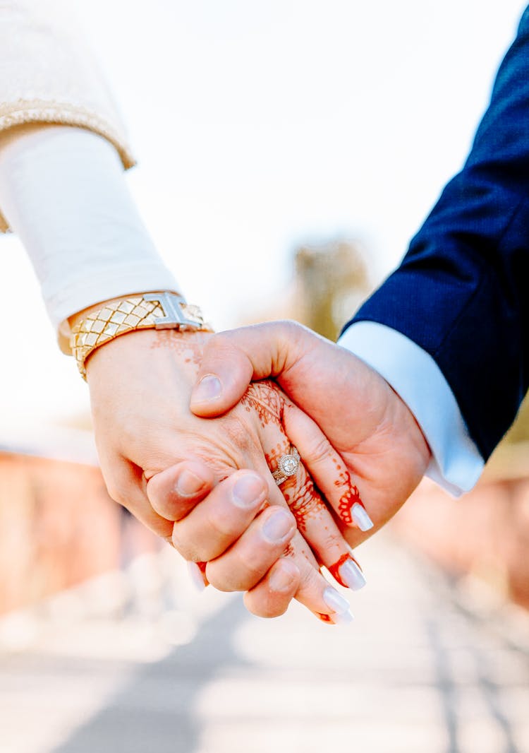 Close-Up Shot Of A Wedding Couple Holding Hands Together