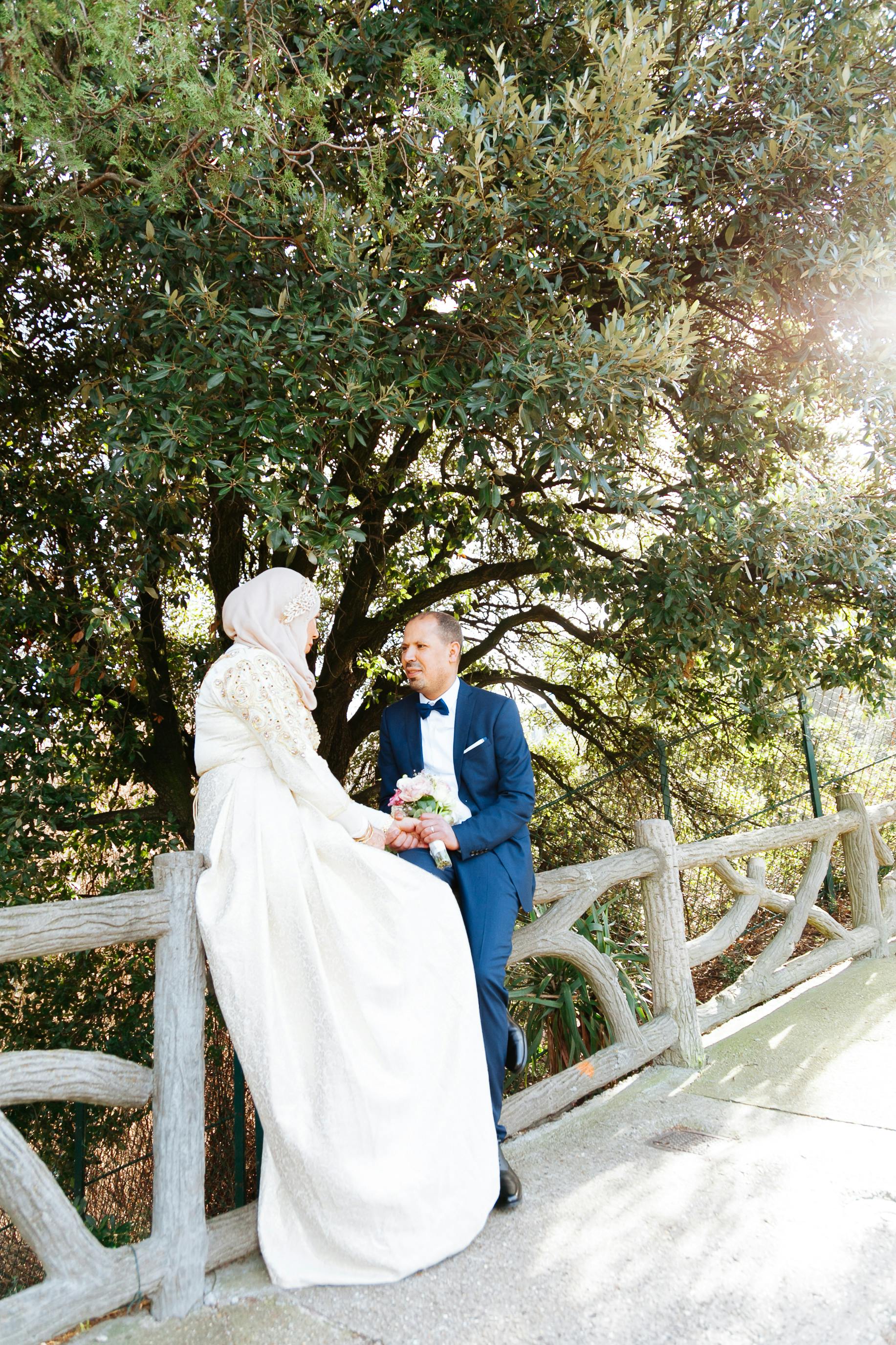 bride and groom standing on a bridge and looking at each other