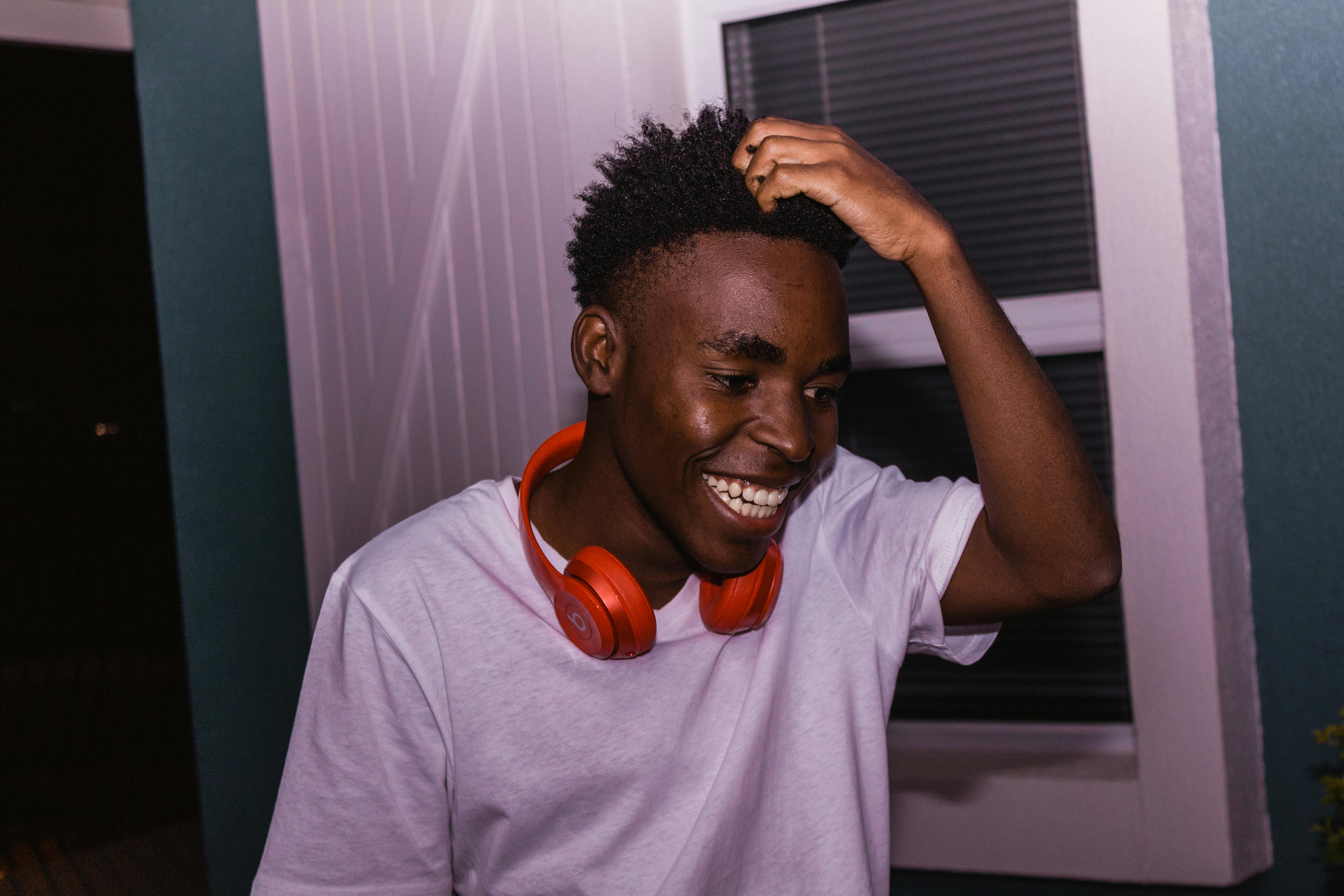 一个开朗的年轻人在室内戴着耳机微笑，散发着欢乐和幸福