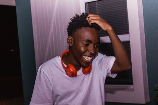 一个开朗的年轻人在室内戴着耳机微笑，散发着欢乐和幸福