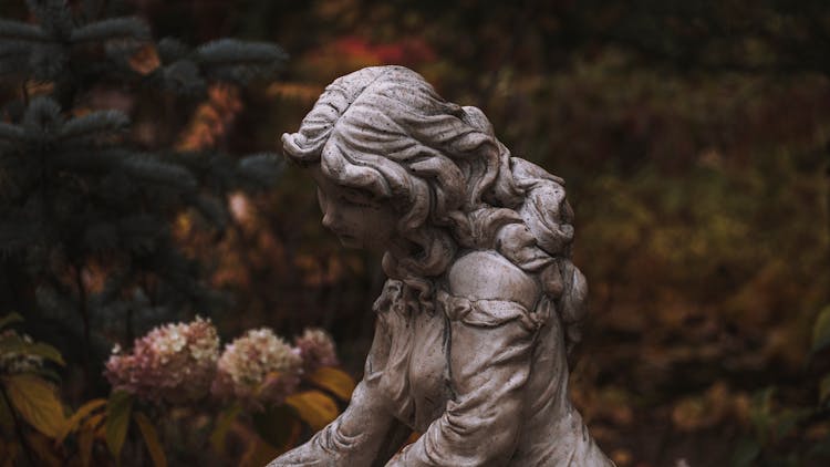 Statue Of Young Girl Surrounded By Flowers