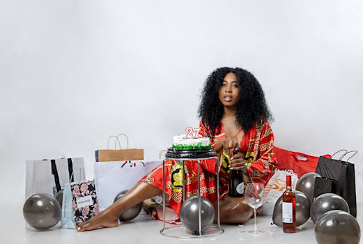 A young woman celebrates her 27th birthday in a studio with balloons, gifts, and a cake.
