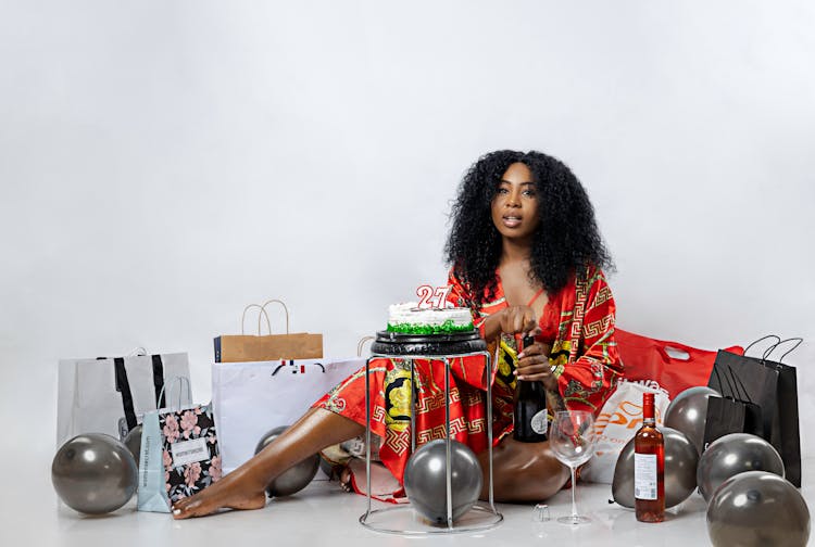 Woman Sitting Next To A Cake, Balloons And Gifts On Her 27th Birthday 