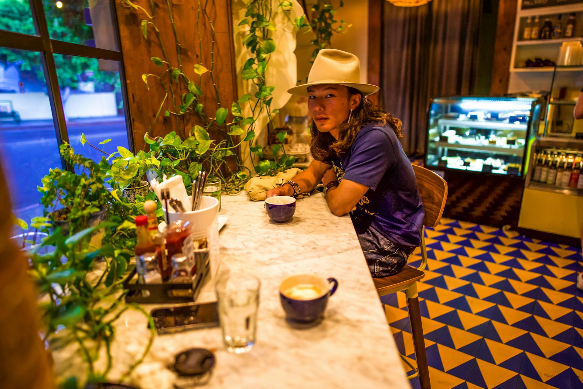 A man with a fedora enjoying a coffee at a stylish Los Angeles café.