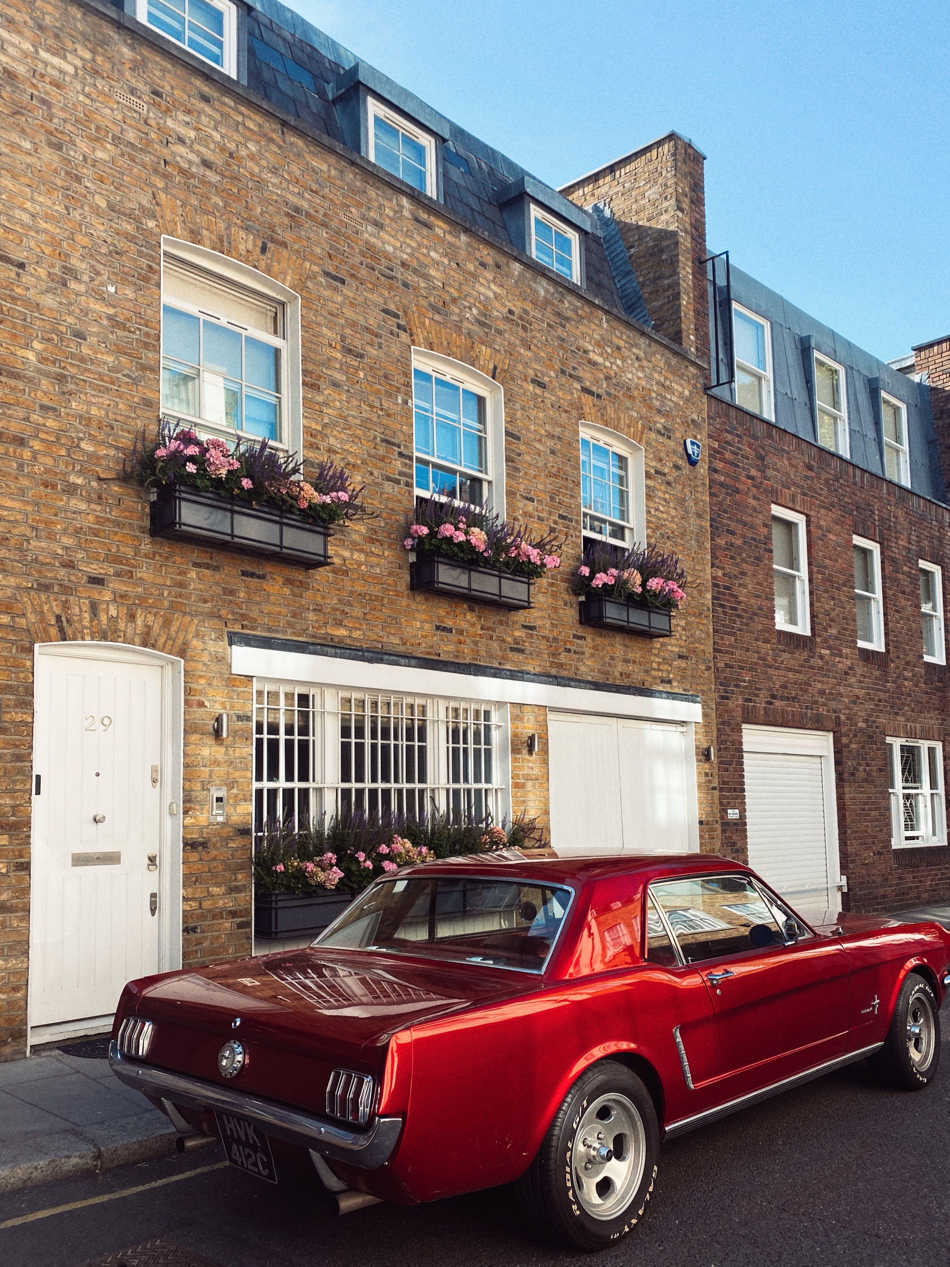 Red Car Parked in Front of Brown Brick Building · Free Stock Photo