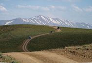 Capture of a dirt road leading through a stunning mountainous landscape with snow-capped peaks.