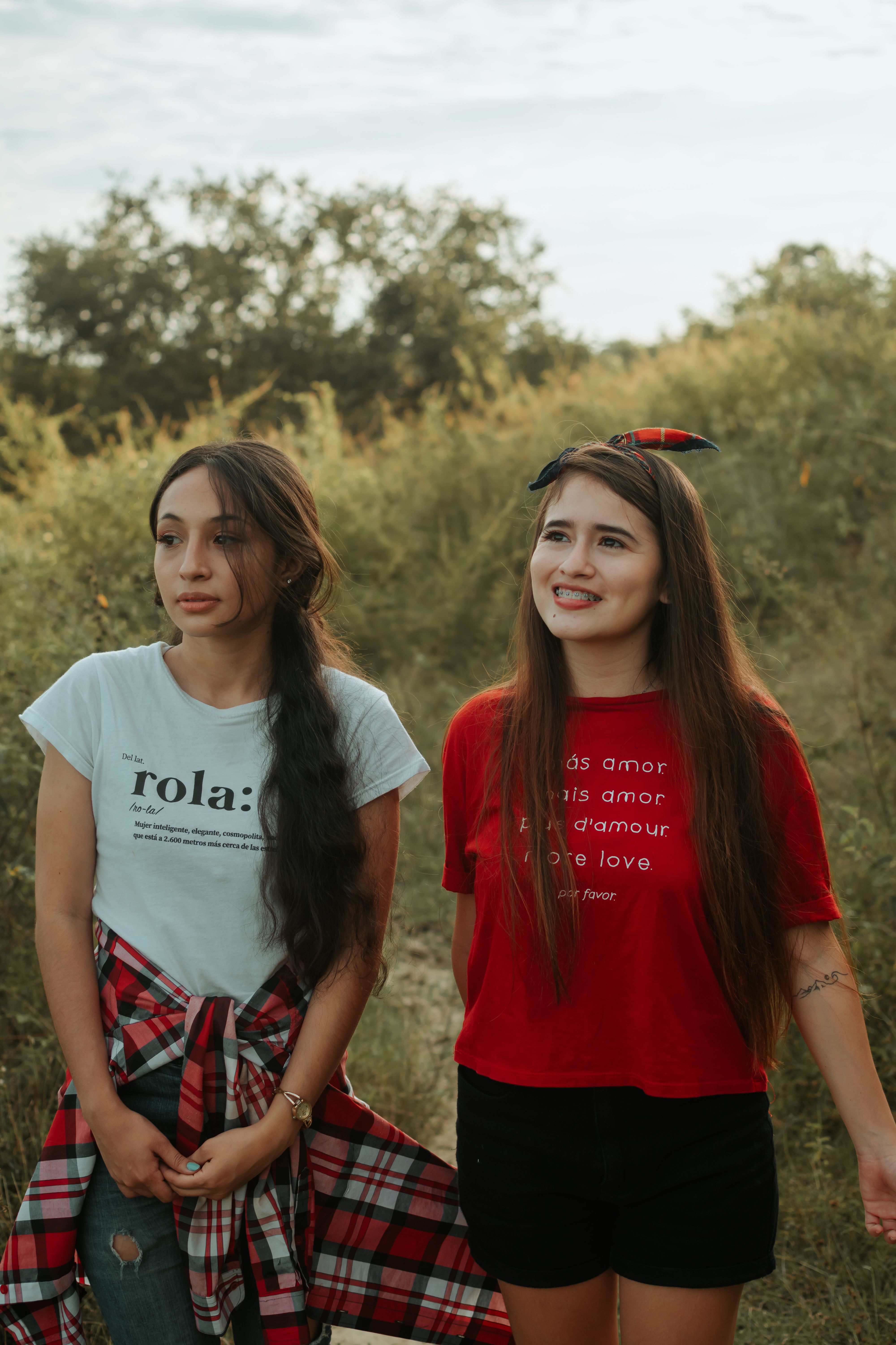 Two women standing together outdoors in a grassy field, smiling
