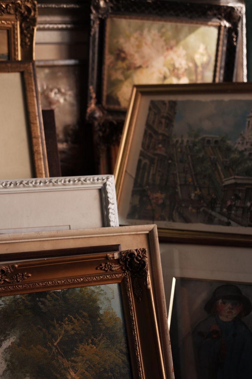 A close view of a collection of vintage framed paintings showcasing diverse art styles.