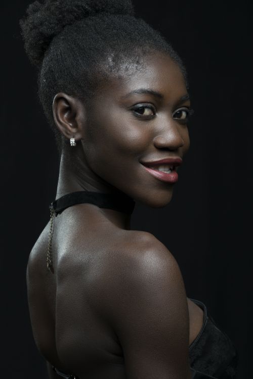 Free Chic portrait of a smiling African woman against a black background, showcasing radiant confidence. Stock Photo