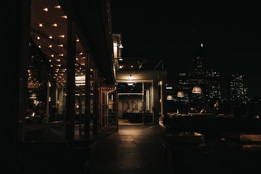 A stylish rooftop bar at night with a city skyline view and ambient lighting.