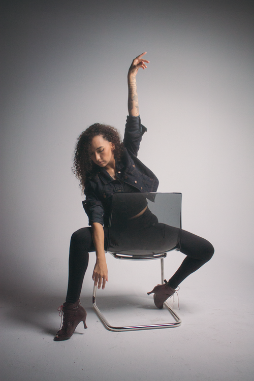 Free Stylish woman poses in a studio environment with arm raised, showcasing fashion and confidence. Stock Photo