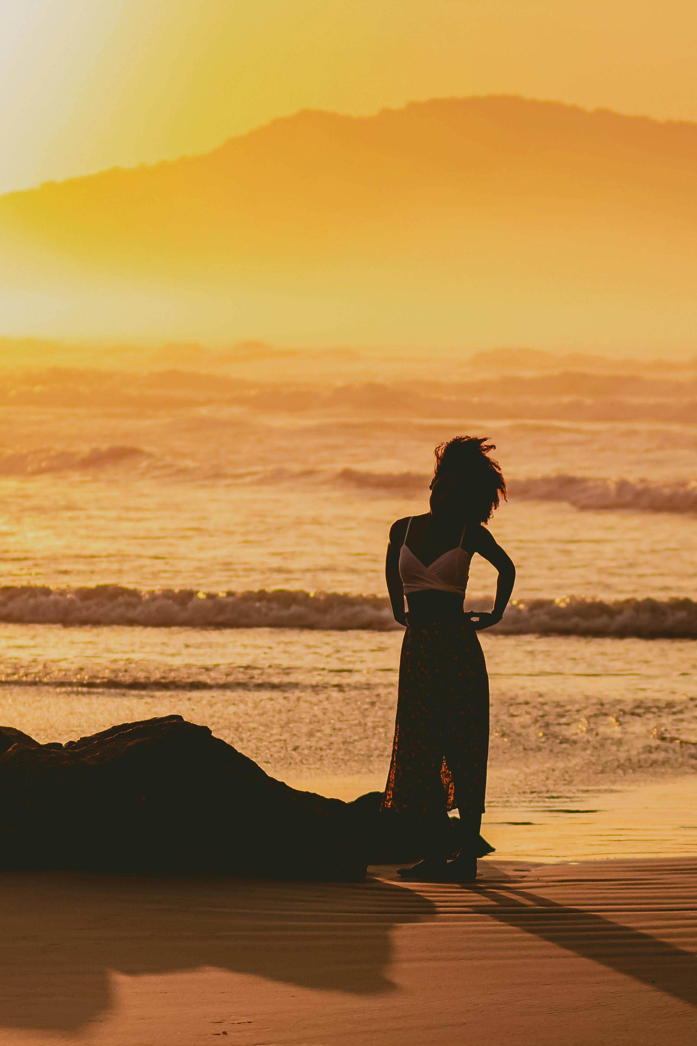 woman standing on a beach at sunset