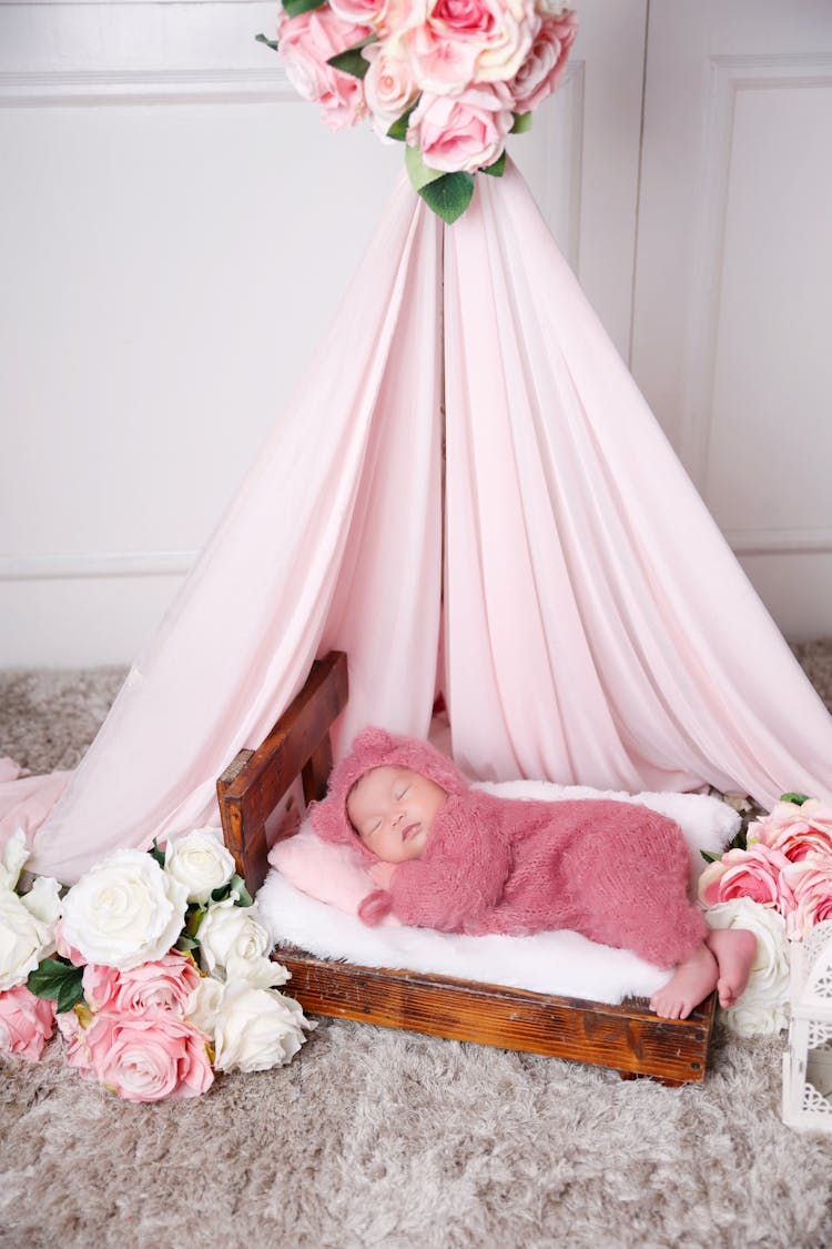 Sleeping Baby In Pink Romper Lying On White Bed