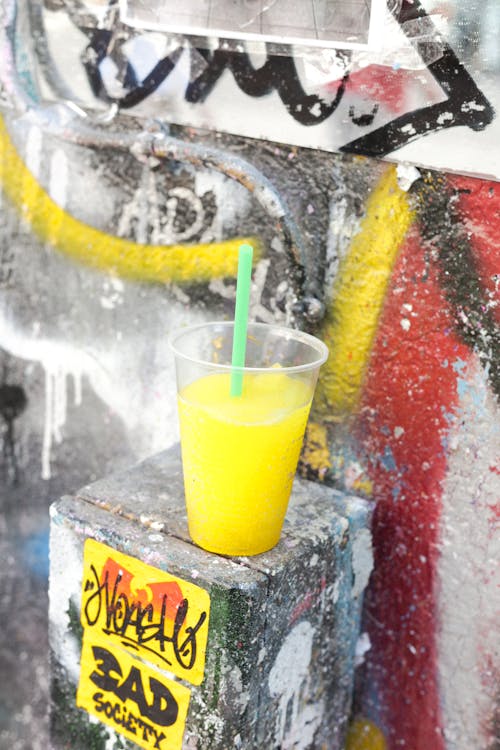 Foto stok gratis cairan kuning, dinding beton, gelas plastik
