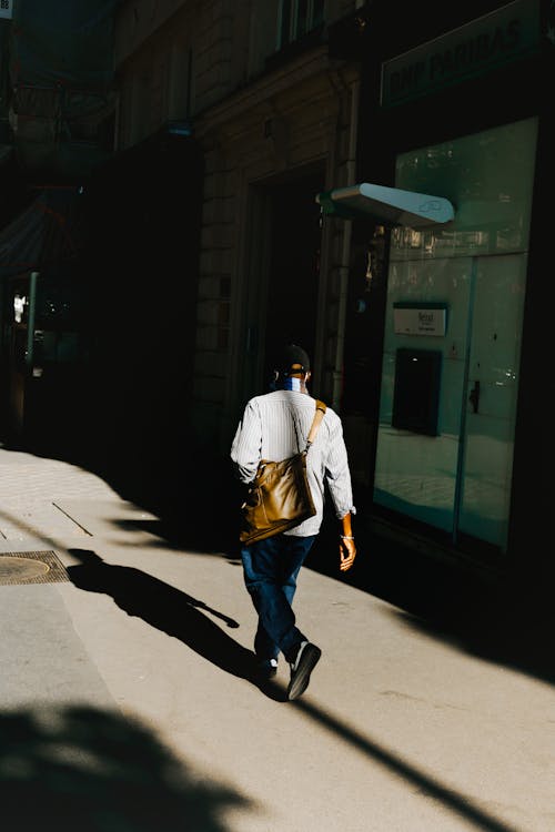 A Man in White Long Sleeves Walking on the Street