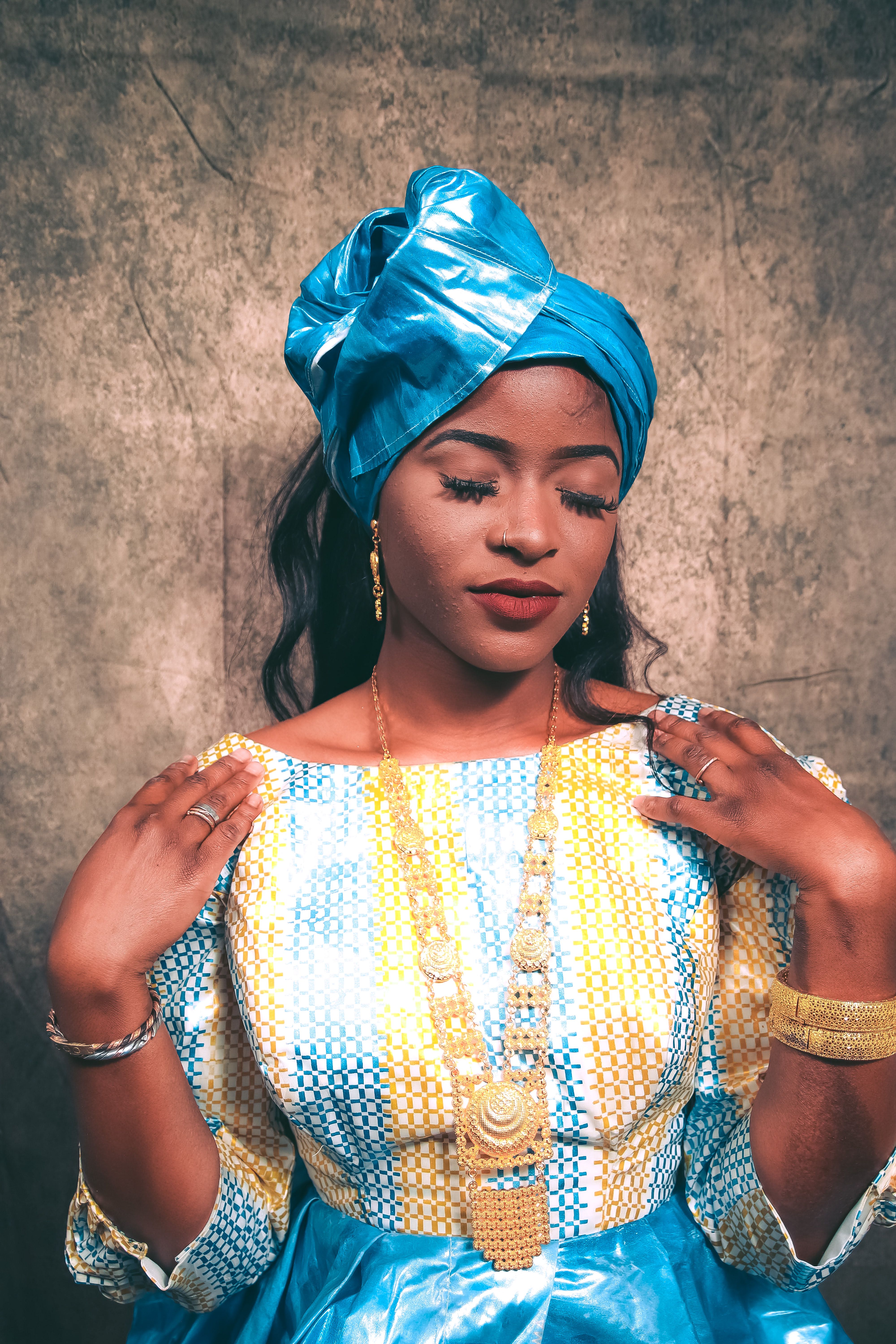 Portrait of a beautiful woman in traditional African dress with a blue headscarf, studio shoot.