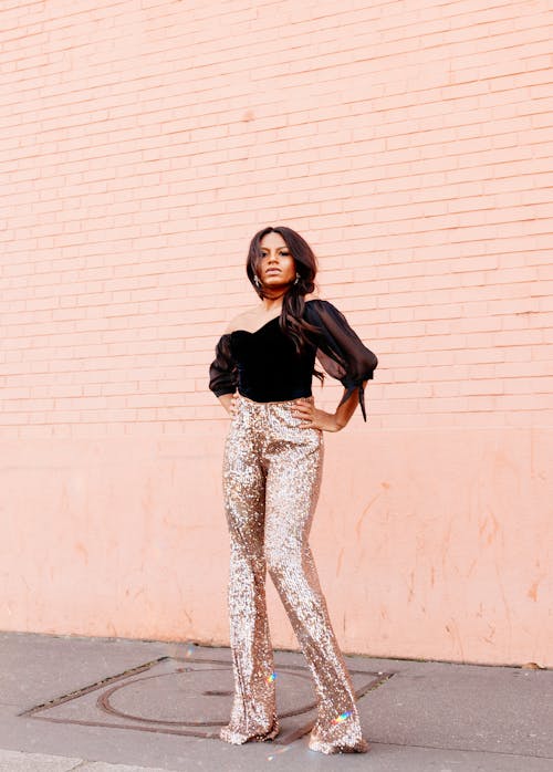 Woman in Pink Sequin Trousers Standing on the Background of a Pink Wall 