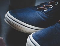 Close-up of navy canvas sneakers with white foxing tape — photo by Omar Markhieh on Pexels