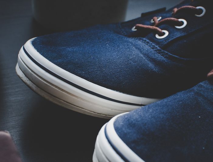 Close-up of navy canvas shoes with white soles — photo by Omar Markhieh on Pexels