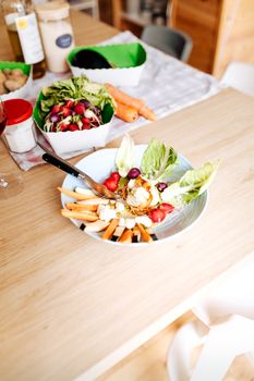 Close-up of a colorful, fresh salad with carrots and lettuce on a wooden table indoors.