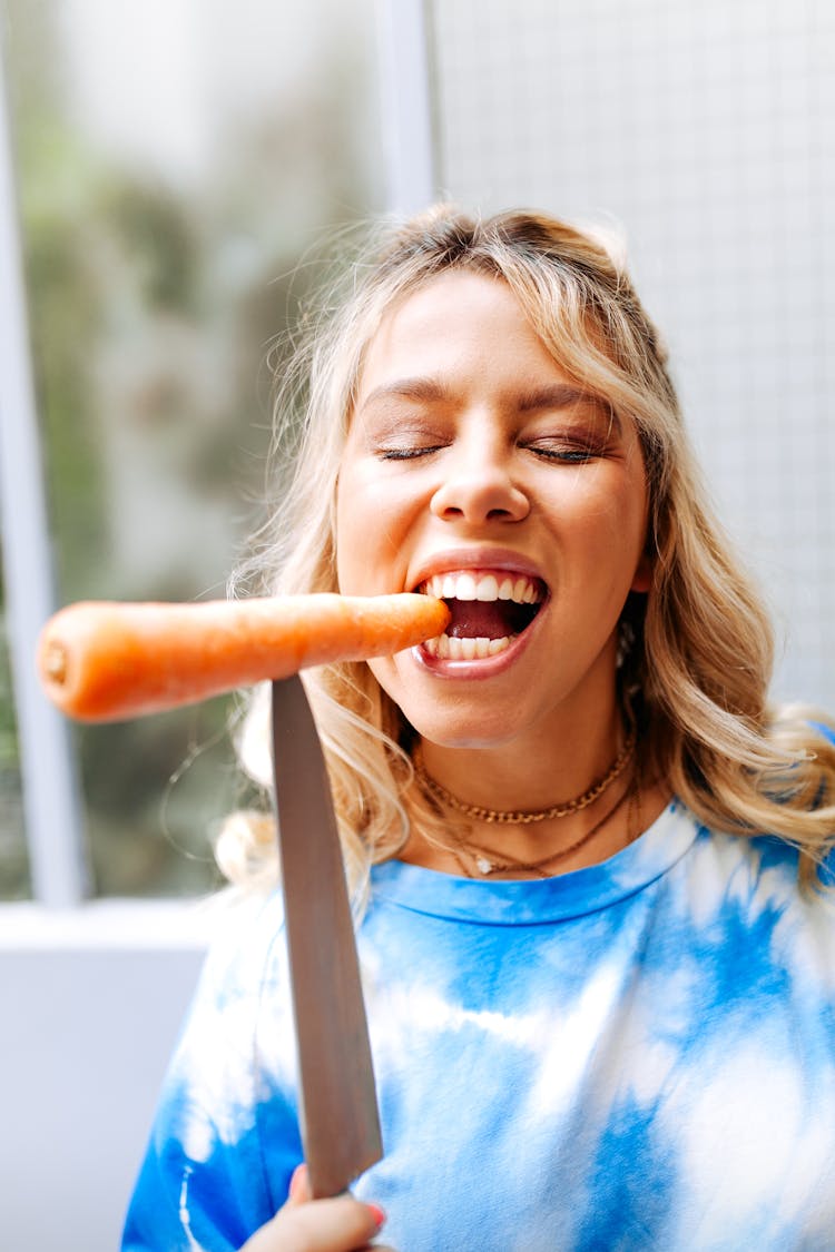 A Woman Biting A Carrot 