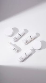 Overhead view of minimalistic skincare products on a white background, creating a clean aesthetic.