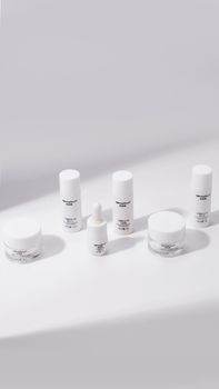 White cosmetic bottles and jars arranged in a minimalist style on a white backdrop.
