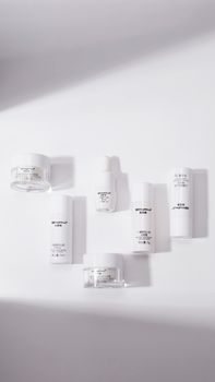 Elegant minimalist shot of white cosmetic products with artistic shadows.