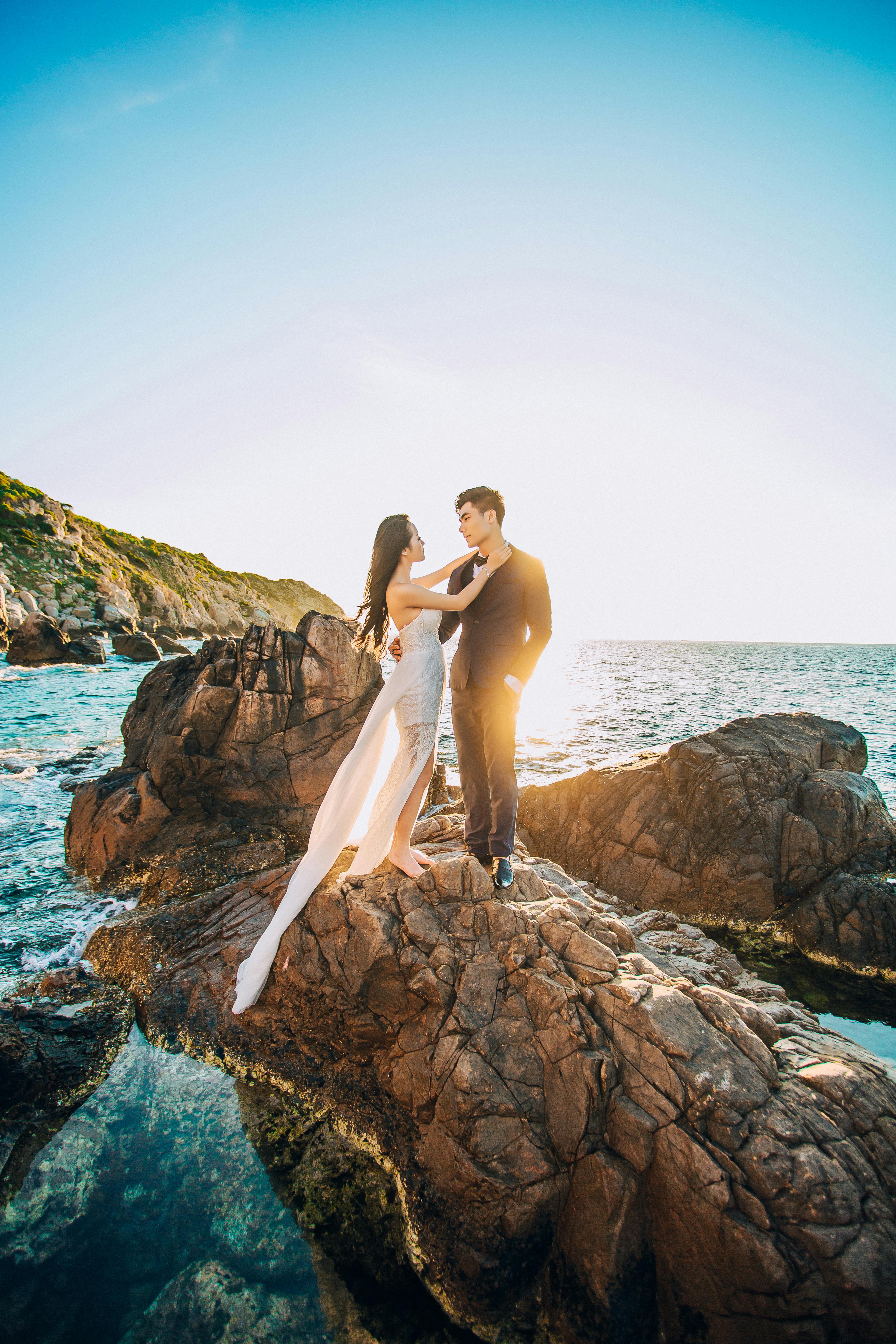 man and woman standing on brown rock under blue sky