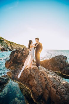 一对夫妇在越南晴朗的天空下，于岩石海边拍摄婚礼照片