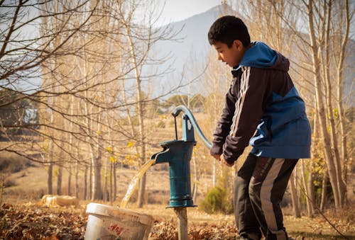 A Boy Pumping Water in a Rural Area
