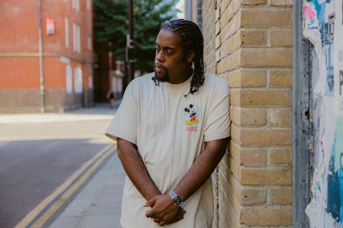 Man in Crew Neck T-shirt Standing Beside the Brick Wall