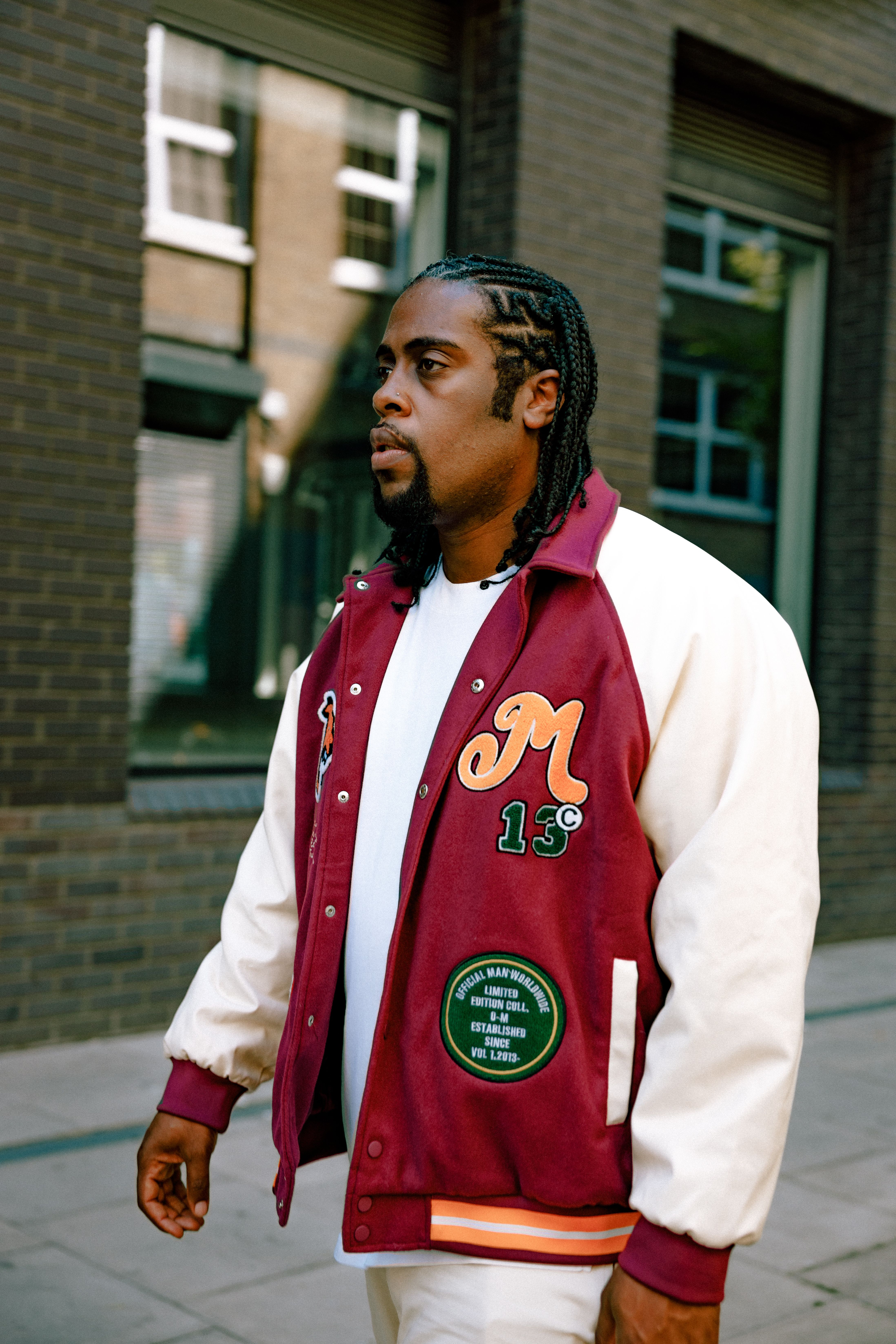 Portrait of a man in a red varsity jacket walking in the city.