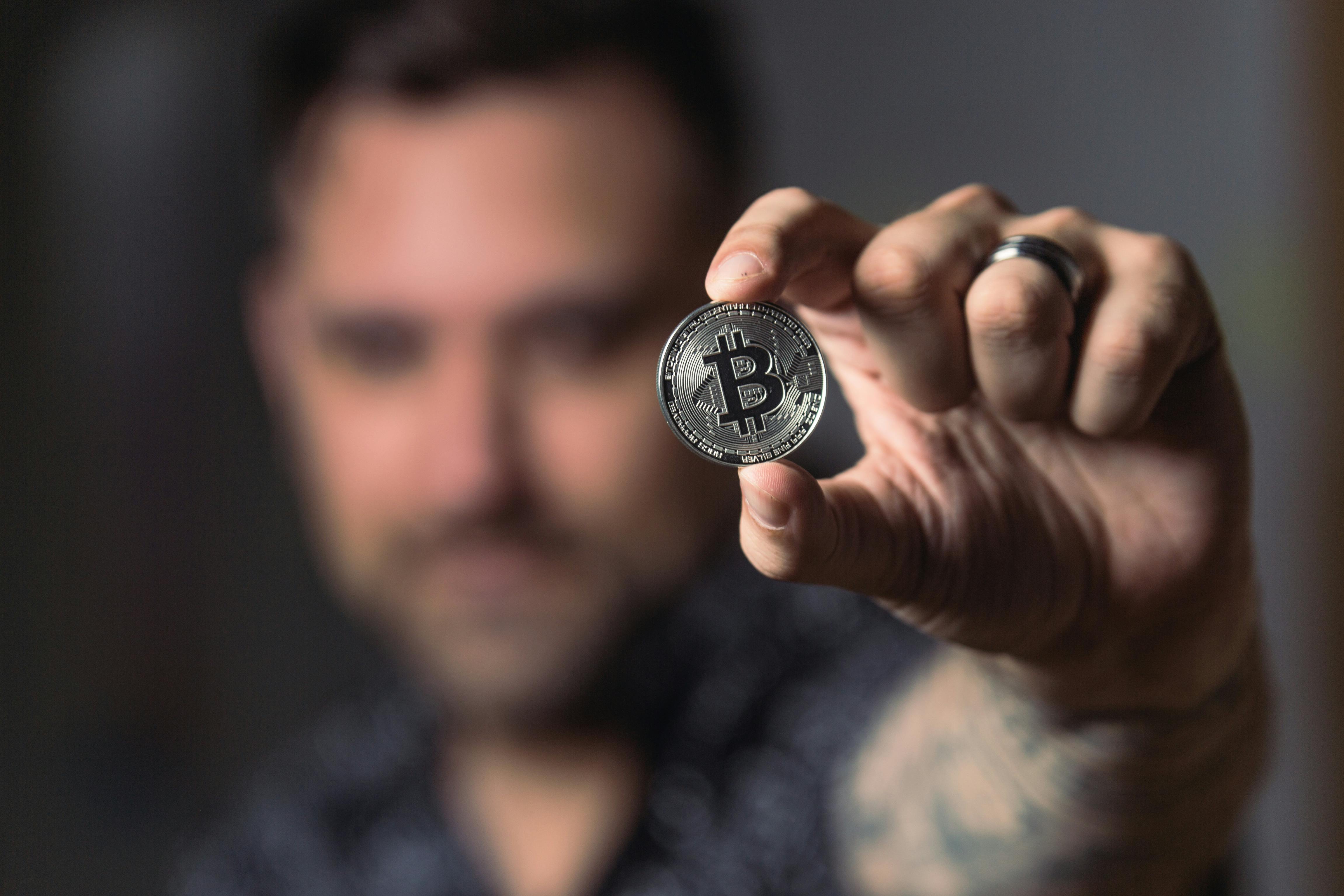 бесплатная Лицо, держащее серебряную монету биткойн Стоковое фото