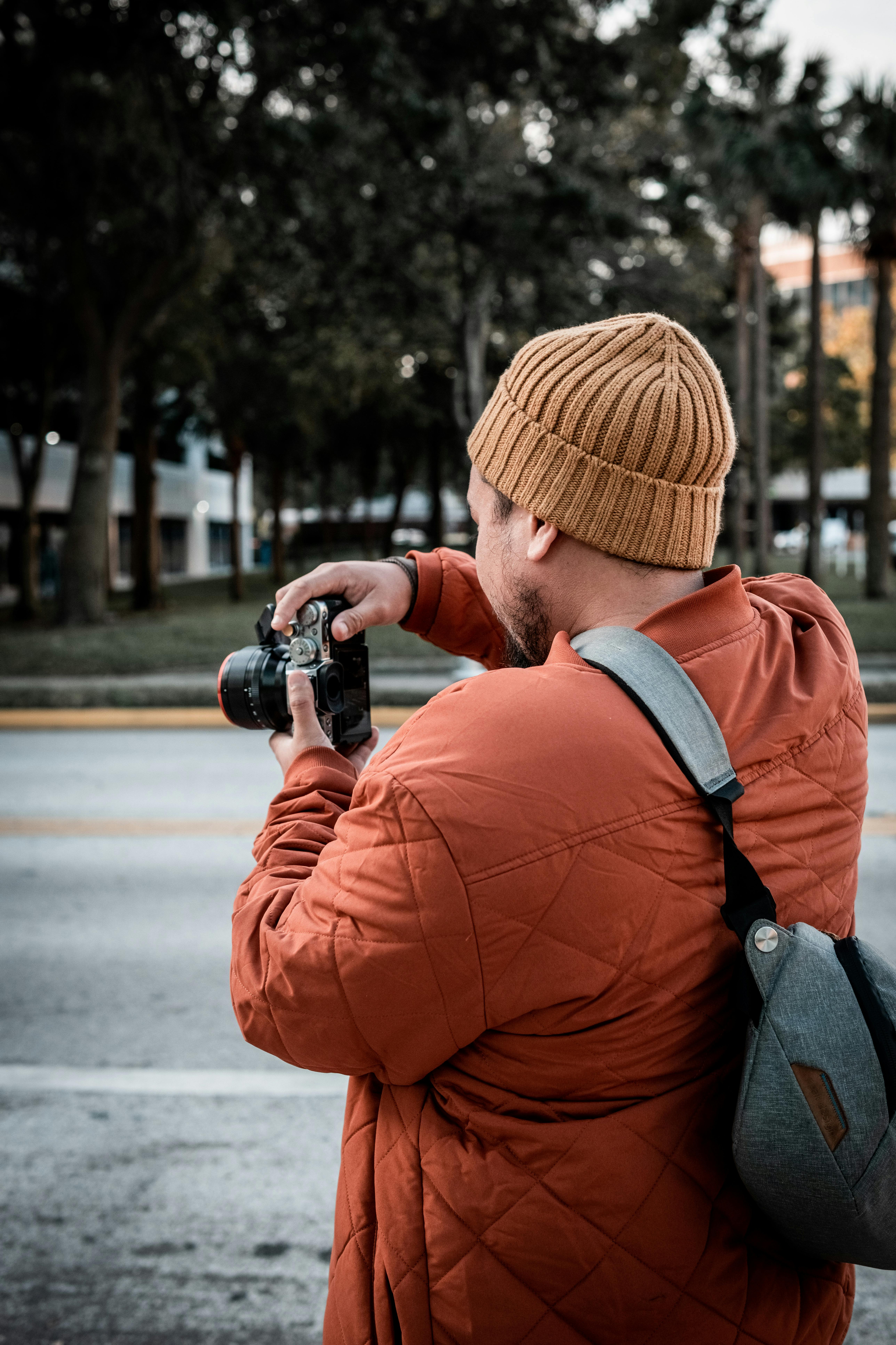 man in brown jacket and blue backpack holding black dslr camera