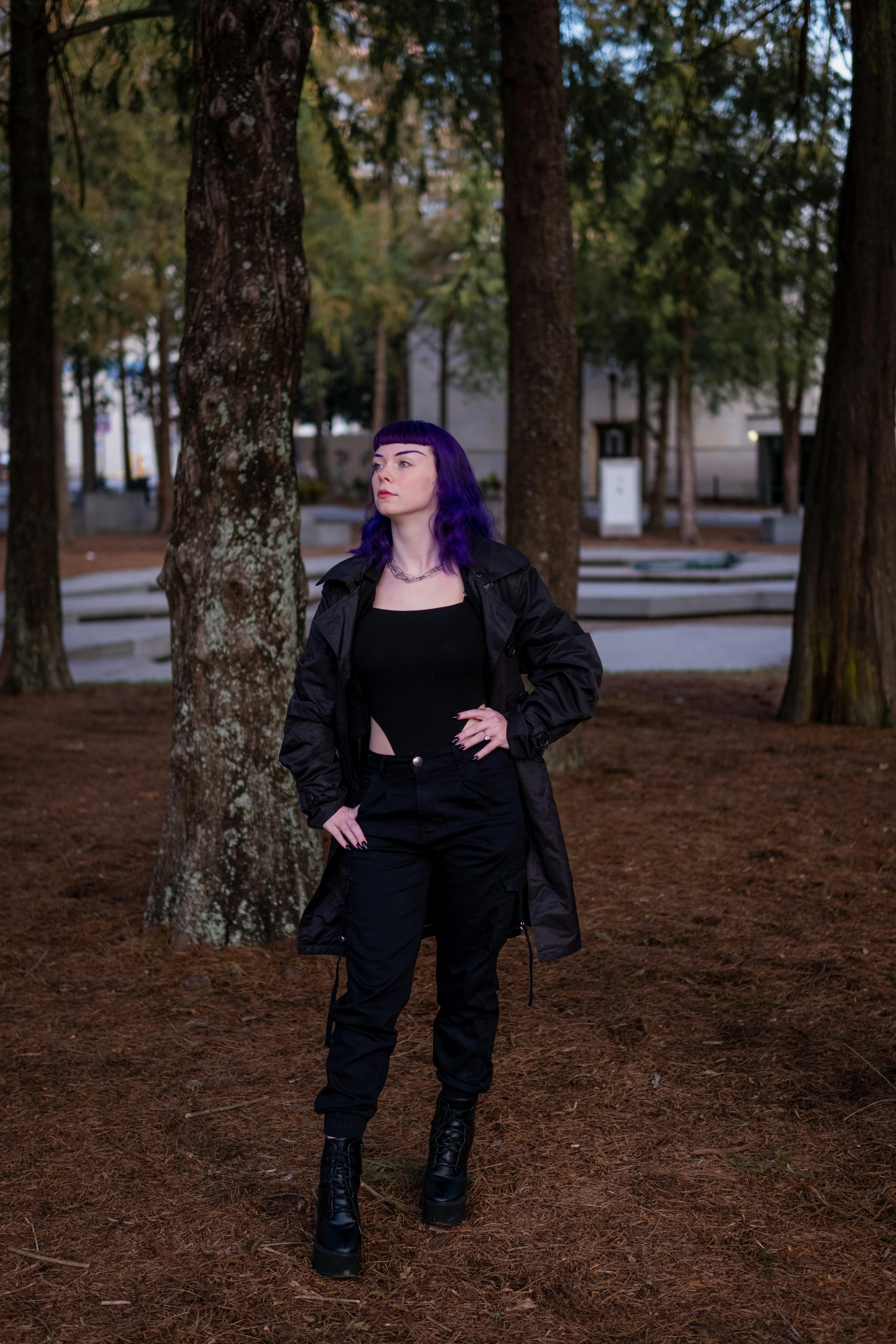 woman in black coat standing near tree